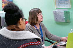 Sally Dreyer, a volunteer through the Retired and Senior Volunteer Program, checks a client in at the St. Vincent de Paul Food Pantry in Indianapolis on Nov. 6. (Still shot from Catholic News Service video by Katie Rutter)